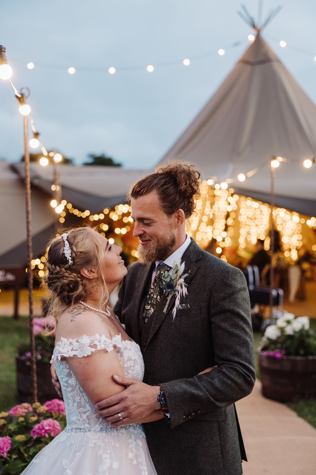 Bride and groom outside tipi lit with fairylights on their wedding day in Staffordshire