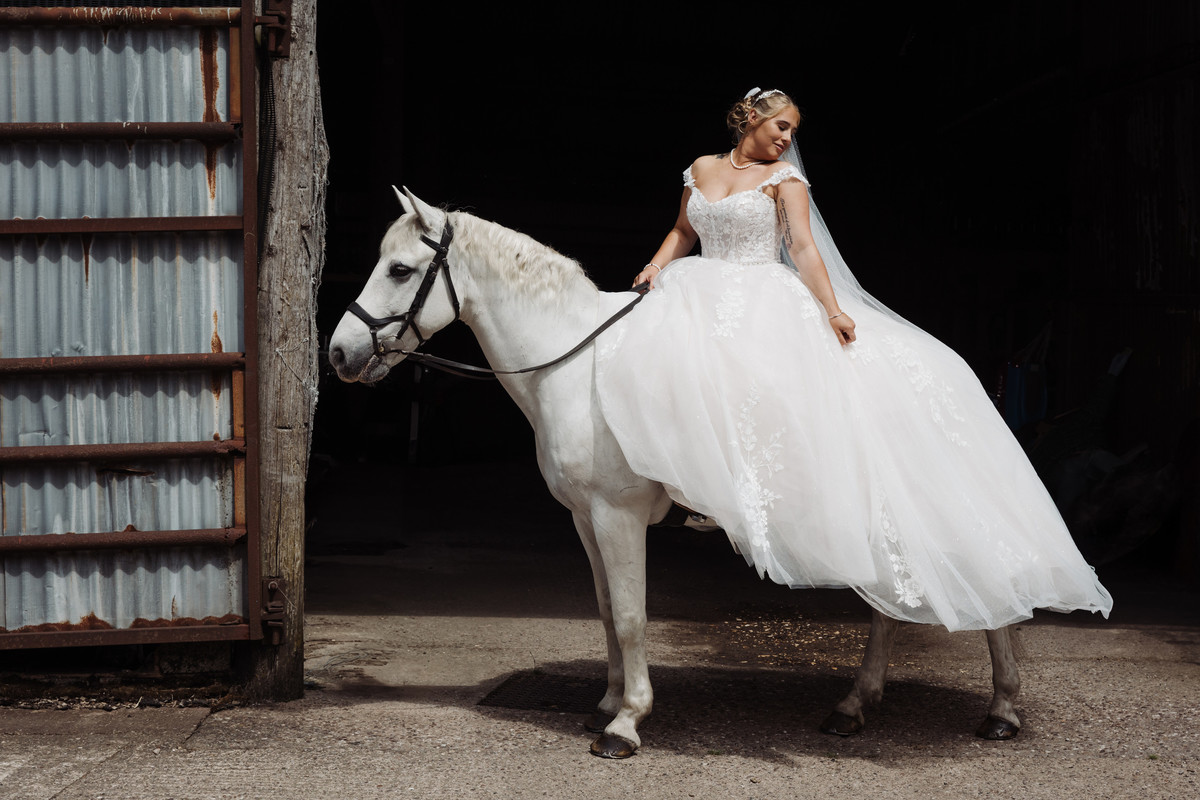 Bride on grey horse in a wedding dress at a tipi wedding in Staffordshire