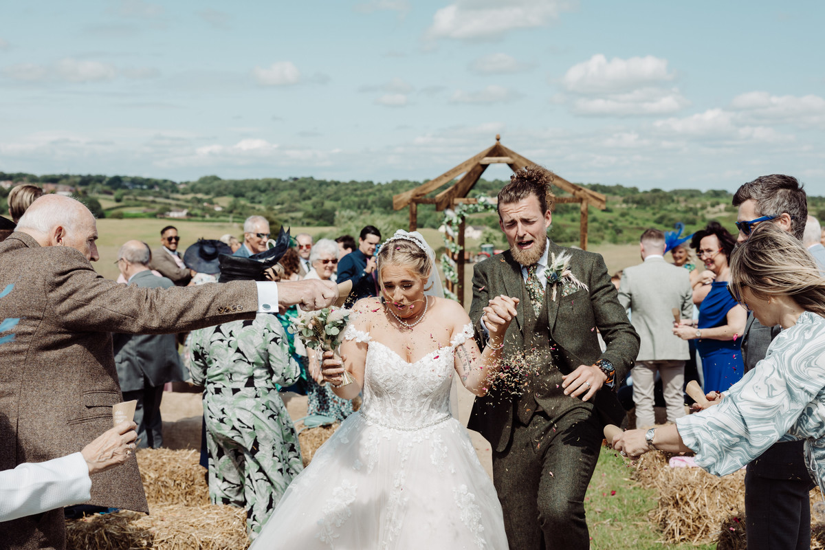Couple grimace as they are pelted with confetti at their Staffordshire tipi wedding