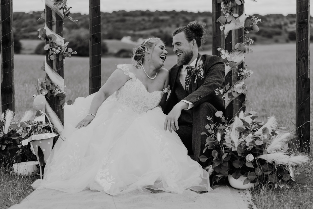 Bride and groom throw heads back in laughter at Staffordshire farm wedding