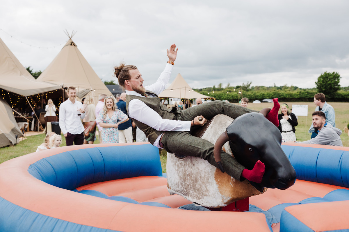 Groom rides rodeo bull on his wedding day at a tipi wedding in Staffordshire