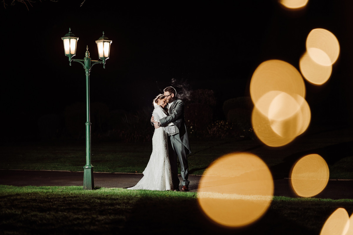 Bride and groom huddle for warmth at a winter wedding at Weston hall