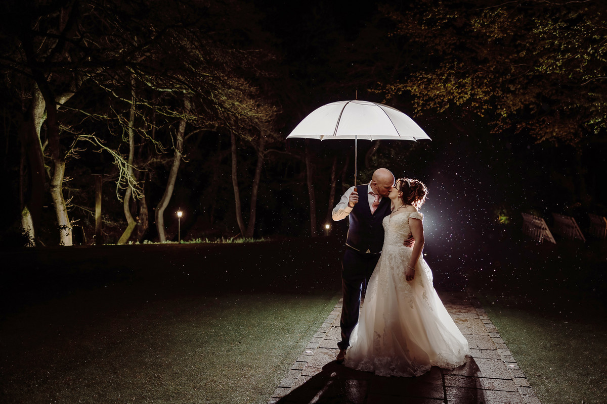 Bride and Groom kiss in the rain at Moddershall Oaks