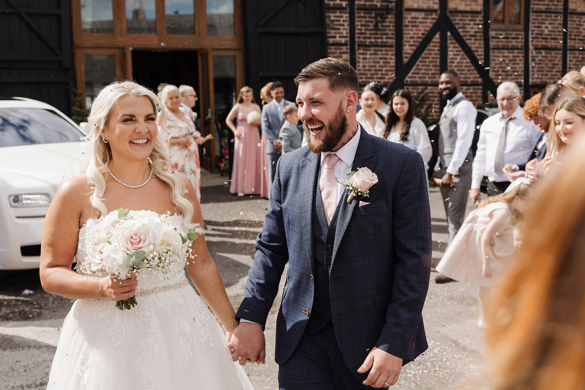 Nikki and Dan smiling after their confetti throw at The Hundred House Hotel
