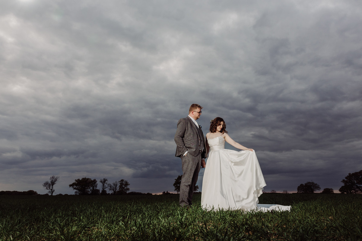 Bride and groom against a stormy sky at Hanbury Wedding Barn
