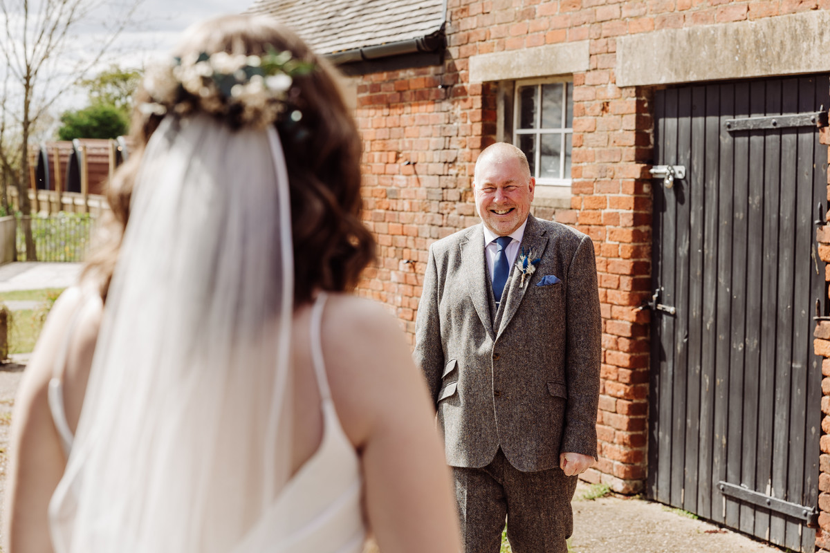 A proud dad smiles at his daughter at Hanbury wedding barns