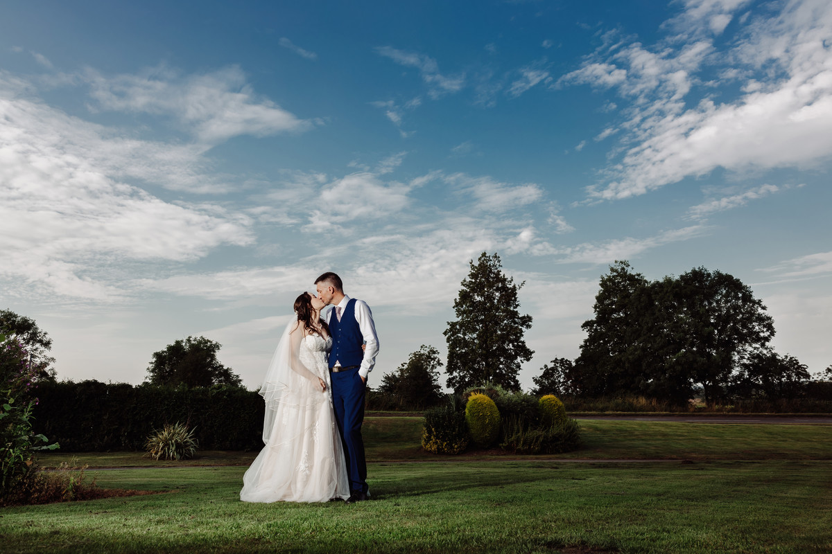 Bride and Groom beneath big blue sky at Weston Hall