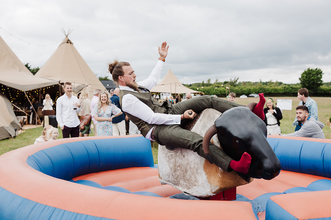 Groom rides rodeo bull on his wedding day at a tipi wedding in Staffordshire