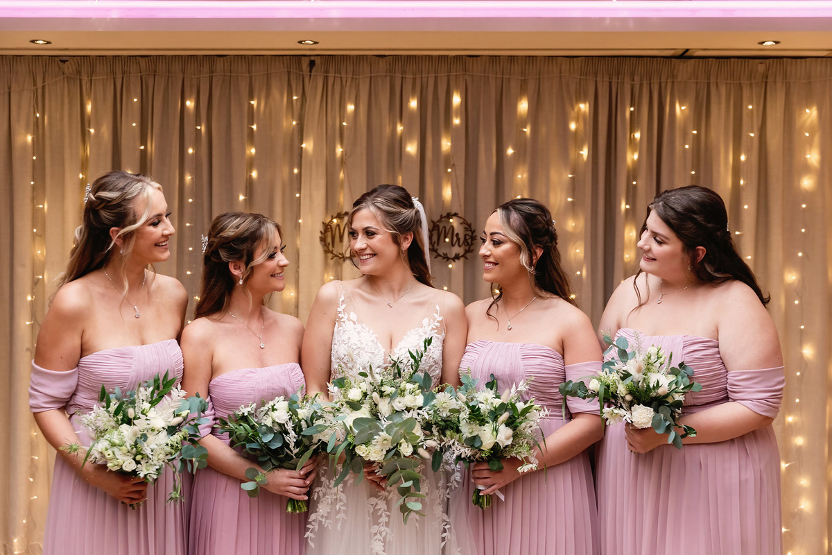The bride and bridesmaids smile at each other at Moddershall Oaks Wedding