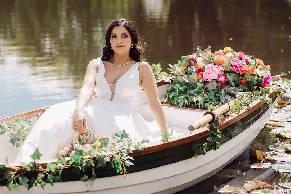 Bride poses in a rowing boat on the lake in Staffordshire