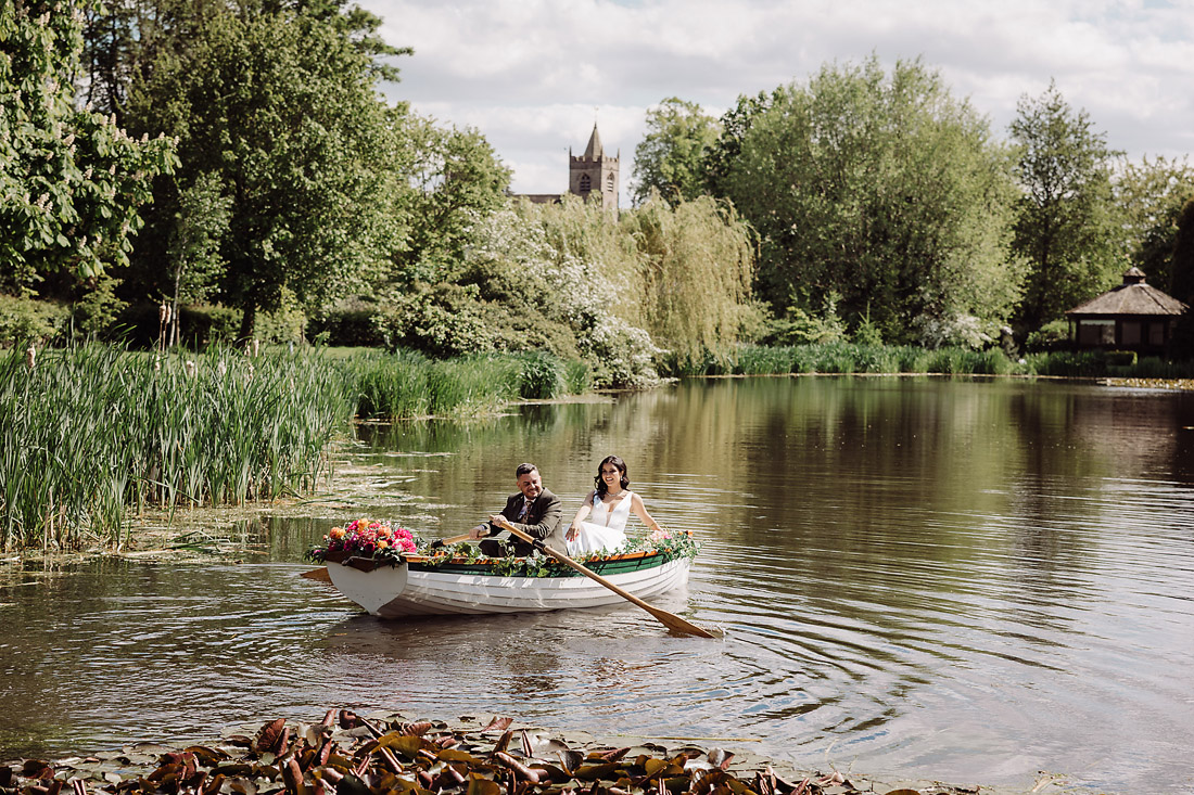 Bride and groom in a rowing boat on the lake at The Moat House