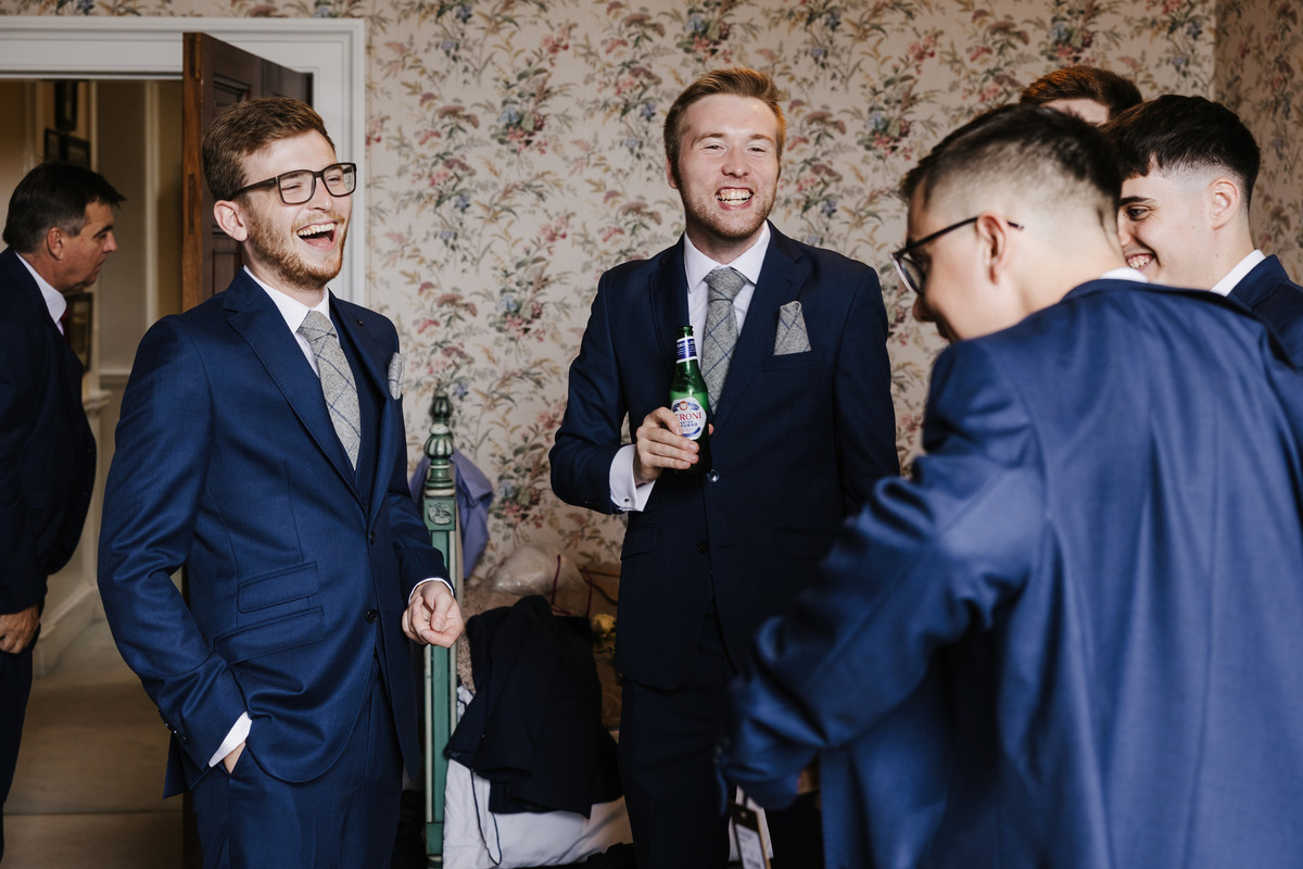The groomsmen laugh and have a beer before the ceremony at Sandon Hall