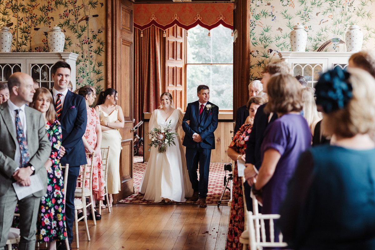 Bride and father make entrance into the drawing room at Sandon Hall
