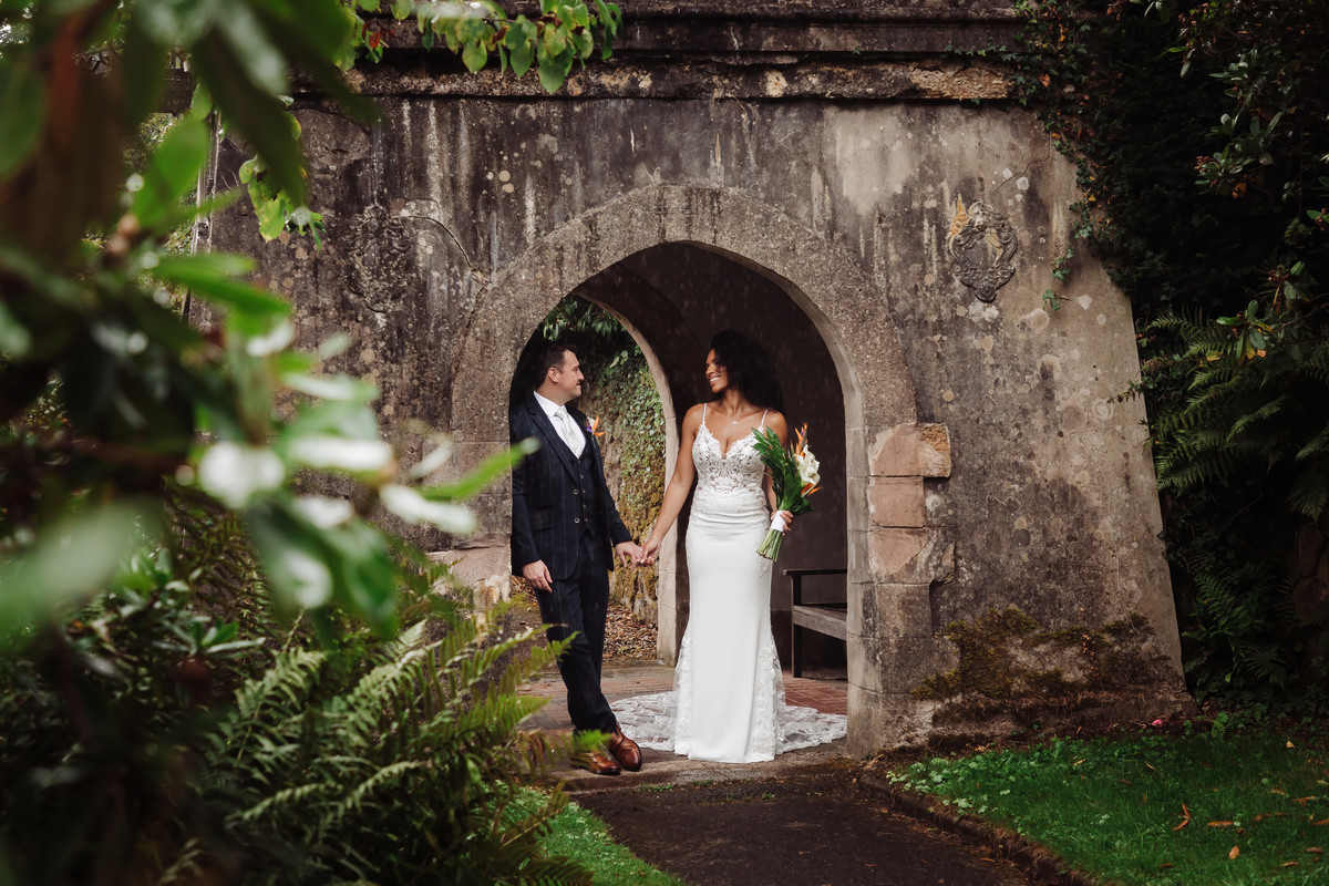 Bride and groom shelter in the gardens at Foxtail barns on a rainy day