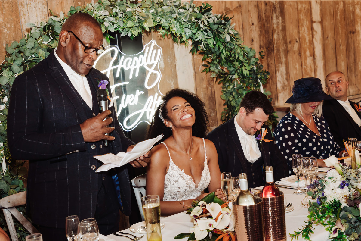 Bride is photographed smiling during father of the bride speech