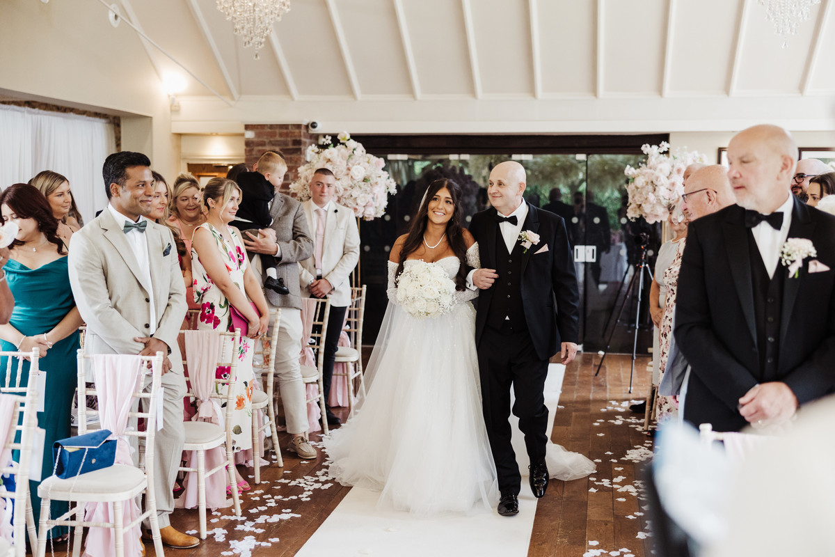 Bride walks down the aisle with Dad in the Orangery at The Moat House