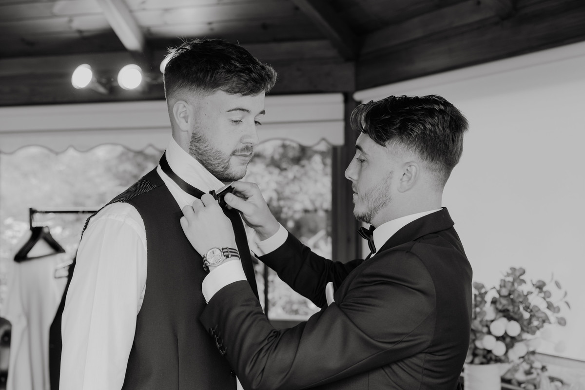 Groomsmen tie a bow tie at The Moat House, Staffordshire