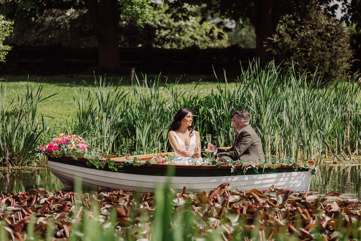 Bride and groom in a rowing boat on the lake at The Moat House