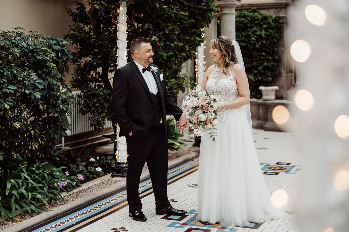 Bride and groom smiling together in the conservatory at Sandon Hall, Staffordshire