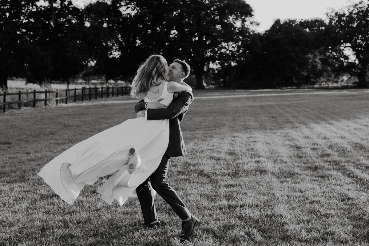 Groom picks bride up and swings her around during couple photographs