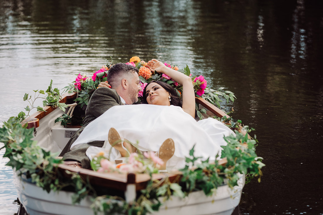 Bride and groom lie together in a rowing boat at The Moat House