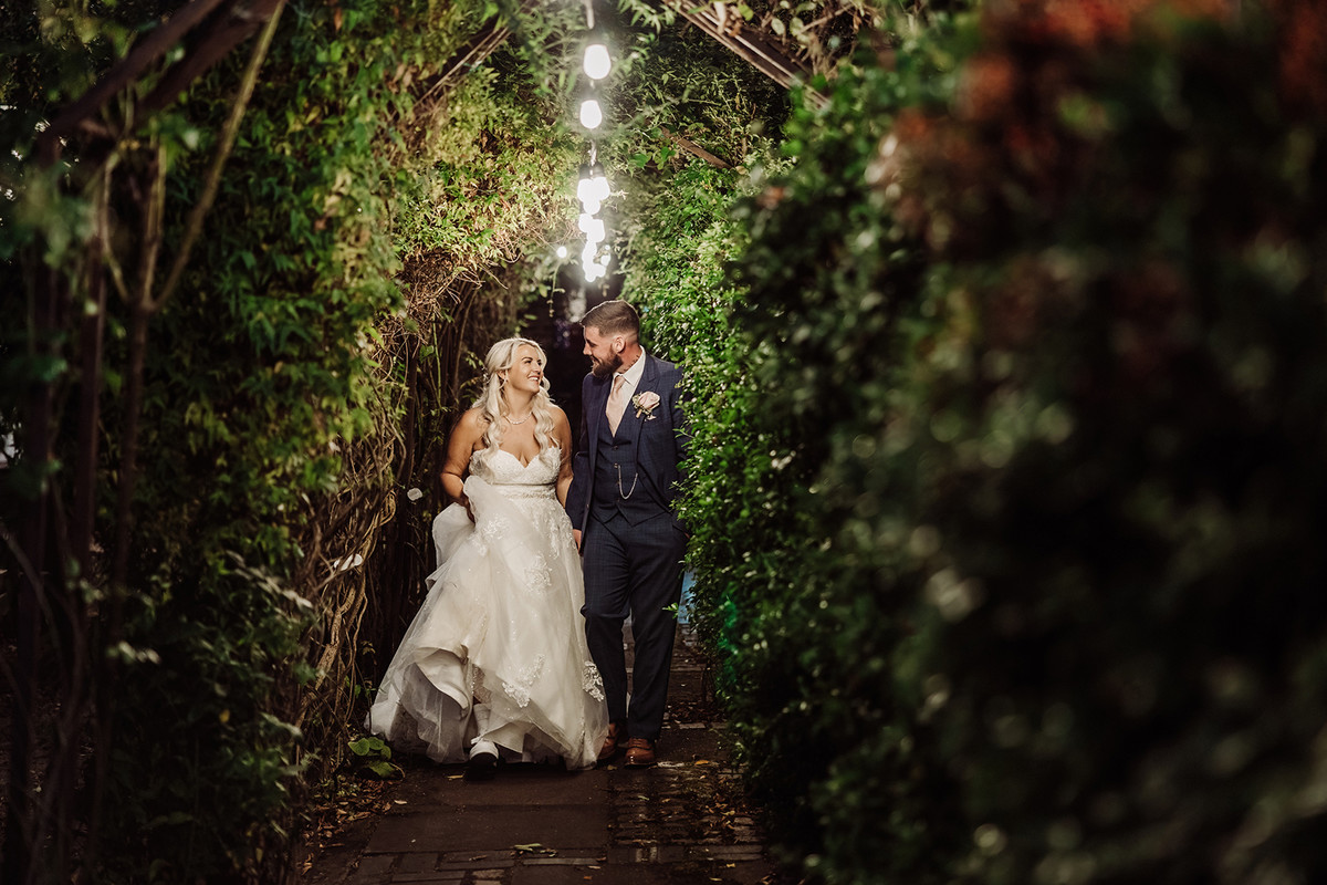 Bride and groom stroll in the gardens at twilight at The Hundred House Hotel in Shropshire