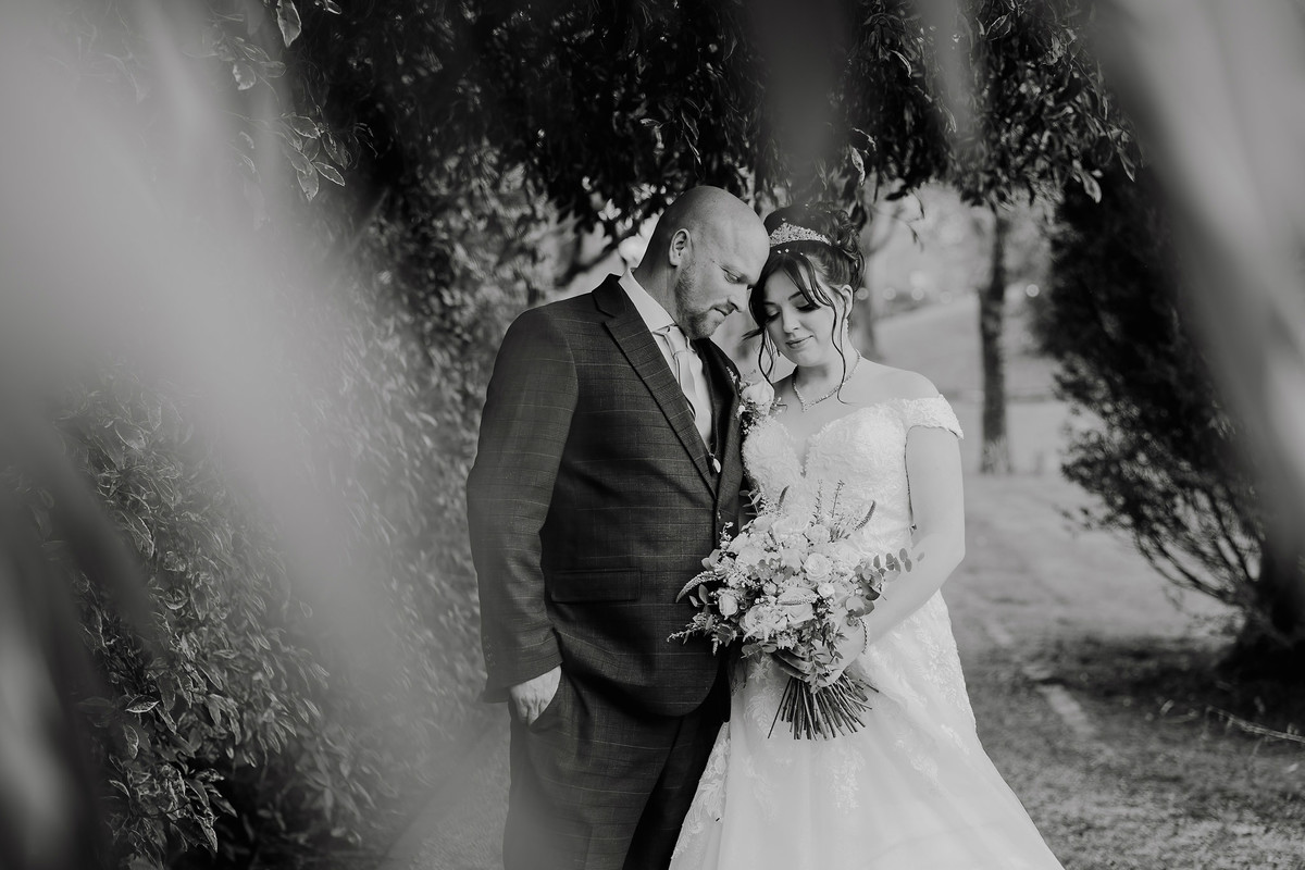 Bride and groom rest heads together in the gardens at Moddershall Oaks